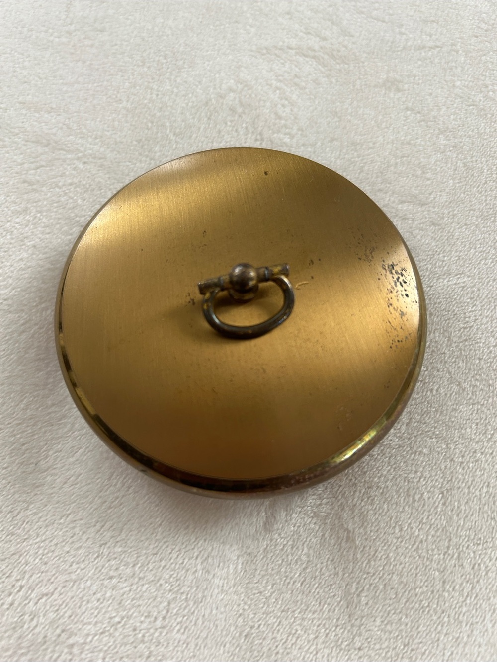 Round vintage compact powder case with footed bottom.